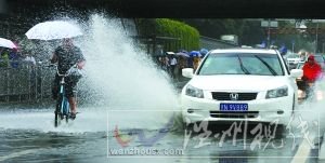 閃 潘家園橋下，汽車掀起的積水飛濺到騎自行車人的身上。本報(bào)記者 尹亞飛 攝