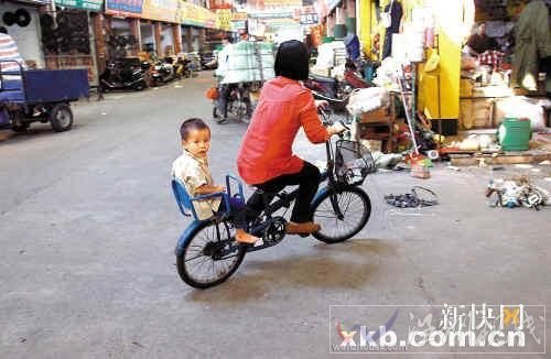 佛山五金市場，一位母親帶著孩子騎車路過事發地點。