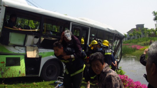公交車被撞到幾十米外的河邊，車體前部受損嚴重。圖為接警后，消防人員很快來到現場，將乘客從車廂里逐個救出。
