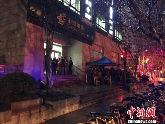 1月5日清晨5點半，在上海靜安郵政支局，市民冒著寒風與冷雨，撐傘排隊，搶購首發(fā)的戊戌狗年生肖郵票。　郭容 攝