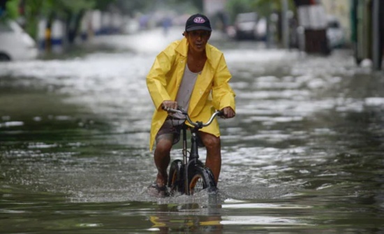 菲律賓暴雨，馬尼拉洪澇災(zāi)害，一名騎自行車的男子涉水穿過被洪水淹沒的街道。
